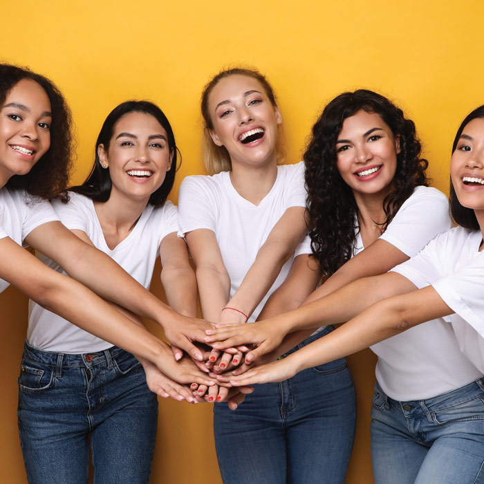 group of happy women putting their hands in for a go team cheer