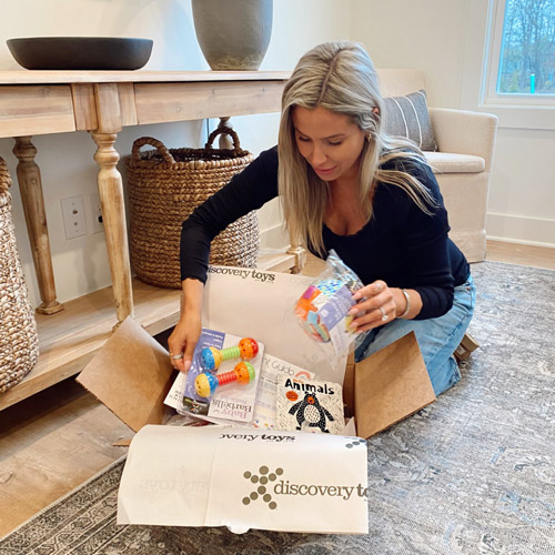 woman opening box filled with Discovery Toys